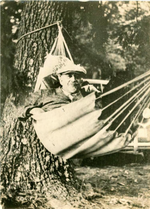 W.E.B. Du Bois reading in a hammock at the camp, c. 1940